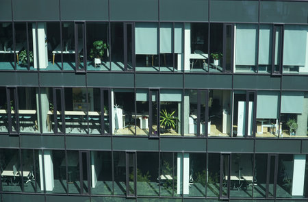 A view of a modern office building, with workspaces visible through the glass facade.の写真素材