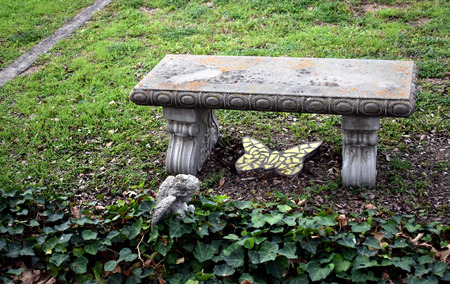 Cement bench with butterfly mosaic, angel and greeneryの写真素材