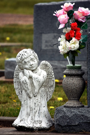 Small child cemetery headstone angel white stone with flowers.の写真素材