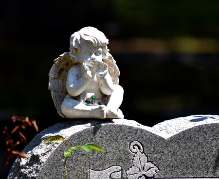 Sitting child angel headstone cemetery sculpture white stone.の写真素材