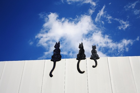 Black cat sculptures sitting on surrounding wallの写真素材