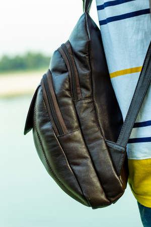 A solid leather bag or carrying bag showing on the man back and stand on the river shore aloneの写真素材