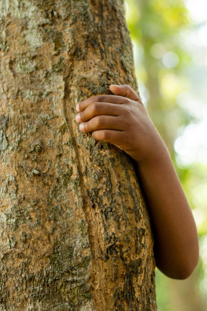 Hiding behind a tree is a man or women holding onto the tree with one hand