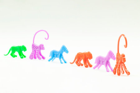 The toys are arranged in a row. There are many small plastic animal toys. The colors of the toys are blue, green, purple, red and pink.の写真素材