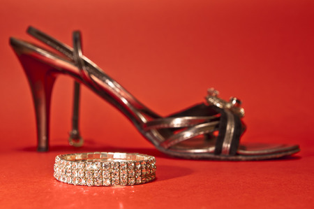 Woman shoe and a bracelet on red background - wealthy Cindirellaの写真素材