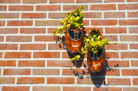 Wooden clog shoes on a brick wall serving as flower pot in the Netherlandsの写真素材