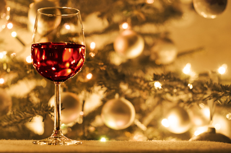 Glass of red wine next to a christmas treeの写真素材