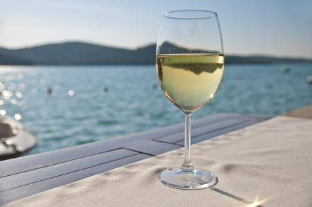 Glass of whitte wine at the bar with beautiful marina in the background.の写真素材