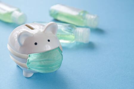 Piggy bank in face mask - costs of pandemics precautions conceptの写真素材