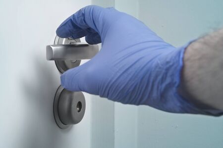 Hand in disposable glove and door handle - pandemics precautionの写真素材