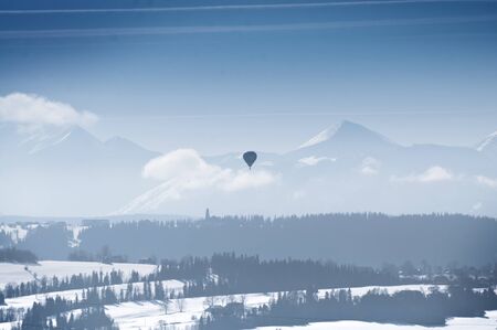 Winter hot air balloon flight over mountains - aviation adventureの写真素材