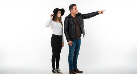 In a stark white studio setting a father and daughter stand side by side gazing towards something intriguing in the distance The father sports a classic leather jacket exuding a cool and confident vibe while pointing emphatically with his right hand guiding their shared focus The daughter chicly adorned with a wide brimmed hat lends an air of youthful curiosity to the scene Their coordinated outfits and expressions suggest a close bond and shared adventure highlighting a moment of discovery and connection between generations Captured in a simple yet impactful composition the image conveys a sense of curiosity anticipation and family unity against the pristine backdropの素材