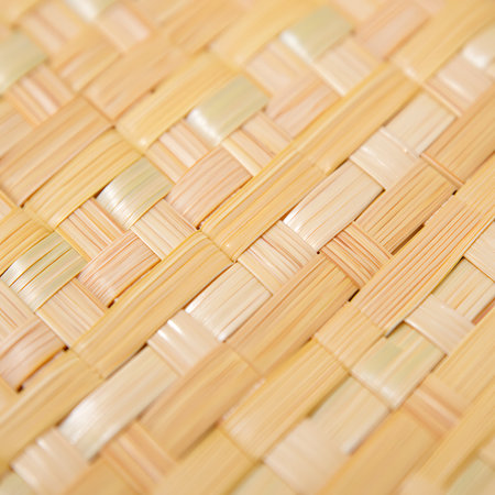 This image provides a detailed close up of a woven bamboo material creating a pleasing diagonal pattern The bamboo strips alternate in shade and create a dynamic visual texture The intricate weave showcases the craftsmanship and natural beauty of the material The texture is perfect for backgrounds and creating a unique visual element for various design projects and brings natural warmth and depth to digital and print mediaの素材