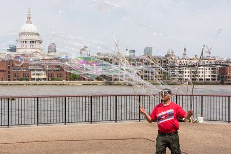 LONDON, UNITED KINGDOM - JUNE 2016 - Street artist peforming his show on waterfront in London. Behind the river, St. Pauls cathedral is visibleのeditorial素材