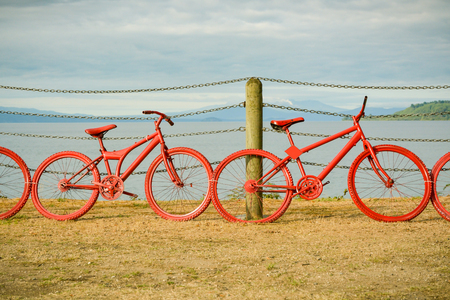 Red painted bicycles propped against the fence near Taupo lake, New Zealandの写真素材