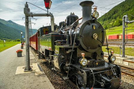 Obergoms, Switzerland - August 16, 2019: Old historic steam train waiting for ride through Furkapass mountain pass on train station in Obergoms, Switzerland during summer 2019のeditorial素材