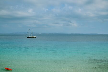 Red kayak and large yacht floating close to beaches in Santa Teresa Gallura in northern part of Sardinia, Italyの写真素材