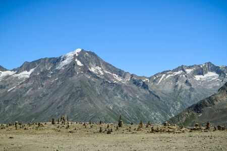 Field with small rock towers and beautiful mountains in background in Langfluh, Switzerlandの写真素材