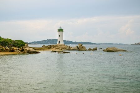 Small lighthouse at the shores of Mediterranean sea in small city of Palau in Sardiniaの写真素材