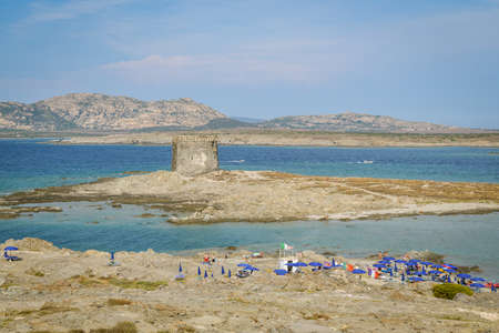 Stintino, Italy - August 31, 2019: People on rocky cliffs close to La Pelosa beach in Stintino, Italy with beautiful views on ancient tower during sunny day in August 2019のeditorial素材