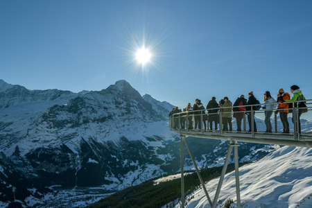 Grindelwald, Switzerland - December 30, 2019: Tourists enjoying views on majestic Eiger peak from outlook in Grindelwald First, Switzerland during sunny day in winter 2019のeditorial素材