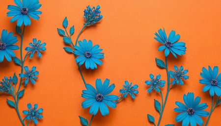 An arrangement of various blue flowers and buds with stems and leaves is presented on a warm orange surface. The composition includes multiple types of blue blossoms, some with more intricate petal structures and others simpler. The vibrant orange background provides a strong contrast, making the blue floral stand out. The captures the essence of a blooming garden with a lively and cheerful color palette.の素材