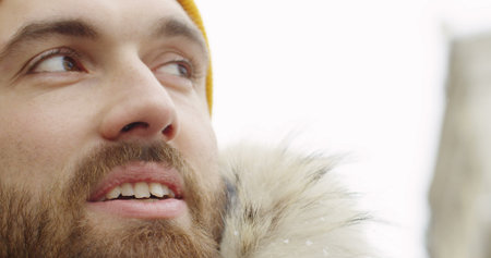 Close up of the male attractive face with a beard wearing a yellow hat and hood with fur. Portrait...