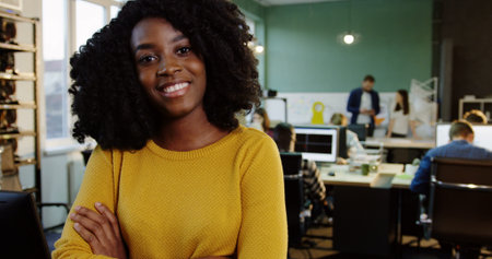 Portrait shot of young attractive curly African American woman smiling into the camera in the modern...