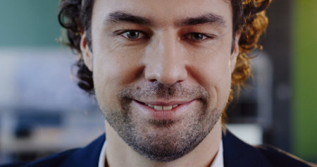 Close up of appealing caucasian man looking into the camera, smiling and taking off his glasses. The...