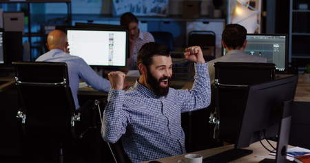 Businessmen and office workers gets excited by job done well on the computer and punches the air in late night.の写真素材