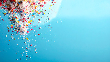 Colorful confetti explosion on blue background. Copy space for text.の素材