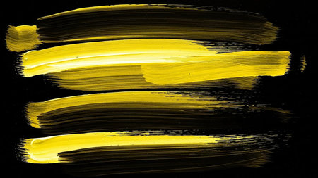 yellow paint brush strokes on black paper background, closeup of photoの素材