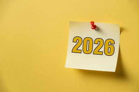 Sticky note displays the year 2026 in bold yellow numbers pinned to a matching yellow wall symbolizing future planning and anticipation of upcoming events. The image evokes a sense of organization anの写真素材