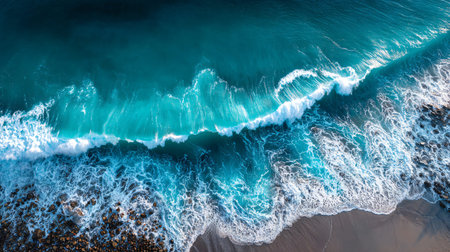 Stunning aerial perspective reveals a vibrant turquoise ocean wave breaking with intense white foam...