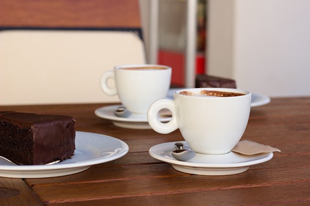 Two white cups of coffee and chocolate desert on the wooden table.の写真素材