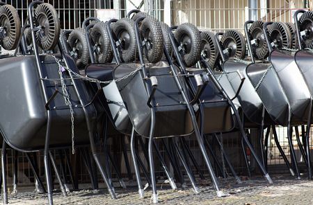 diferent types of black wheelbarrows ready to sell, tied with stringの写真素材