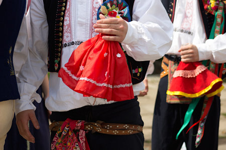 boys in local folk costumes  holding  glass bottle of wine with small red skirt on it