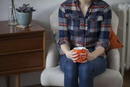 Woman in Plaid Shirt Holding an Orange Mugの写真素材
