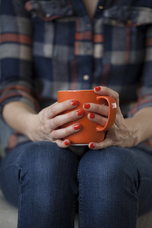 Woman in Plaid Shirt Holding an Orange Mugの写真素材