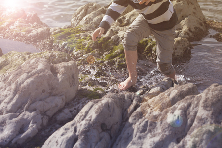 Boy Playing and Exploring in Tidal Pools Near the Oceanの写真素材