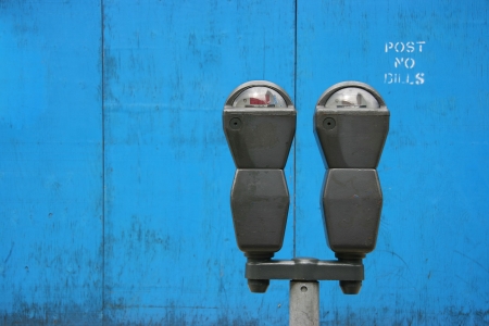 Two parkmeters over blue wooden panels with a stenciled の写真素材