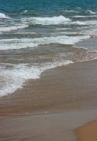 Waves splashing on brown beach, verticalの写真素材