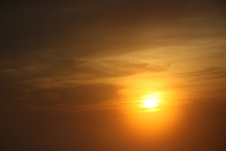 Golden sun at sunset peeking from the cloudsの写真素材