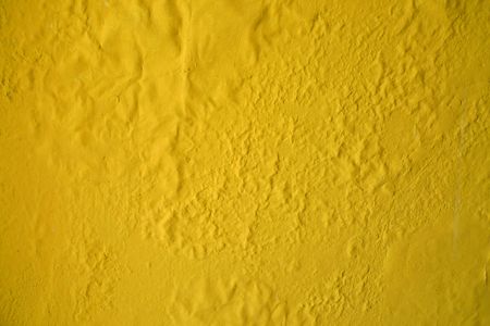 Yellow paint decaying on an old wall backgroundの写真素材