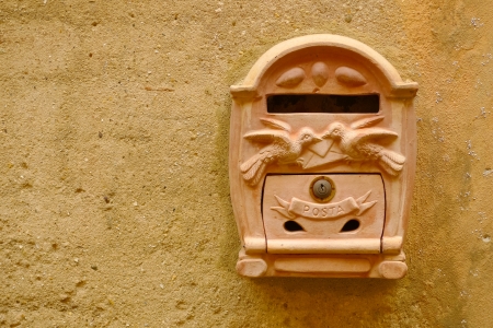 Terracotta mailbox on a yellow wall in Certaldo, Tuscany, Italy.の写真素材