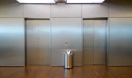 Two brushed metal elevator doors in a minimalistic style building interiorの写真素材