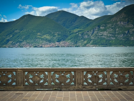 Ornate stone banister on lake Iseo waterfront overlooking Predore, Brescia, Italyの写真素材