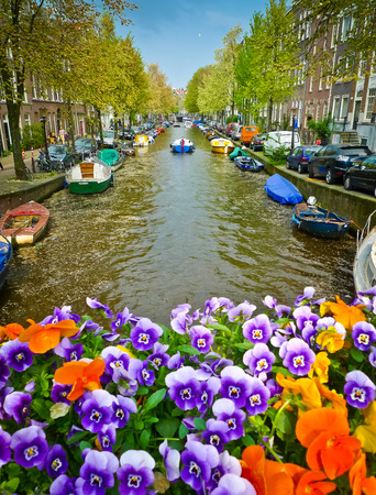 Flowers on a bridge over a canal in Amsterdam, Netherlands. Focus on the canal.の写真素材