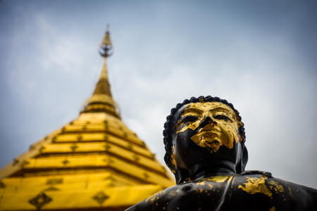 Low angle view of a black and gold Buddha and golden chedi, Wat Phra That Doi Suthep, Chaing Mai, Thailandの写真素材