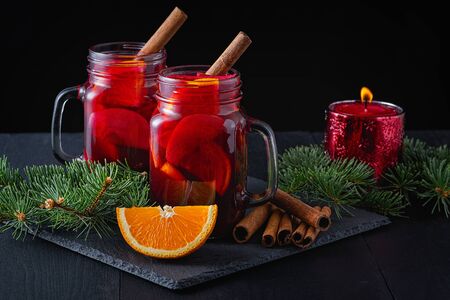 Christmas mulled red wine with spices and fruits on a wooden black rustic table. Traditional hot drink at Christmas timeの写真素材